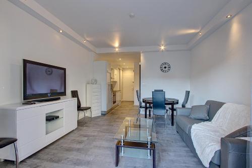 a living room with a couch and a tv and a table at Appartement T2 bord de mer climatisé in Juan-les-Pins