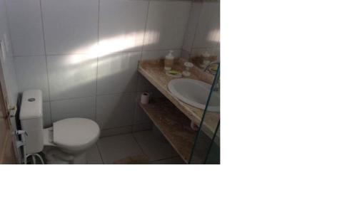 a bathroom with a white toilet and a sink at Casa em Maragogi in Maragogi