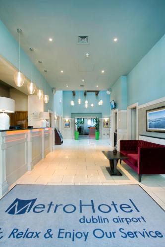 a lobby with a red couch and a kitchen at Metro Apartments Dublin Airport in Dublin