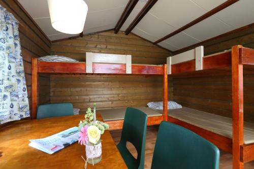 a room with a table and two bunk beds at Camping Recreatiepark Aalsmeer in Aalsmeer