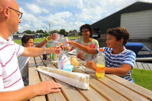 a group of people sitting at a picnic table with drinks at Camping Recreatiepark Aalsmeer in Aalsmeer