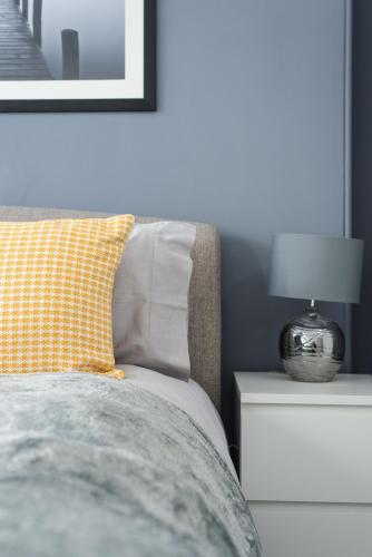 a bed with a pillow and a lamp on a nightstand at The Roseburn Apartment in Edinburgh