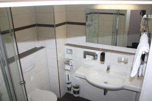 a bathroom with a sink and a toilet and a mirror at Hotel Berlin in Leipzig