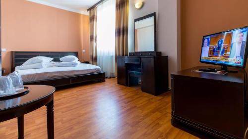 1 dormitorio con 1 cama y escritorio con TV en Hotel Dumbrava, en Rupea