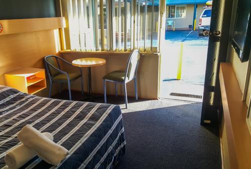 a room with a bed and a table and chairs at Windsor Motel in Windsor