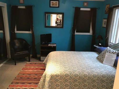 sypialnia z niebieskimi ścianami, łóżkiem i krzesłem w obiekcie Elaine's Hollywood Bed & Breakfast w Los Angeles