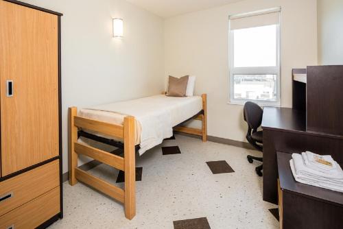 a small bedroom with a bed and a window at UWinnipeg Downtown Hostel in Winnipeg
