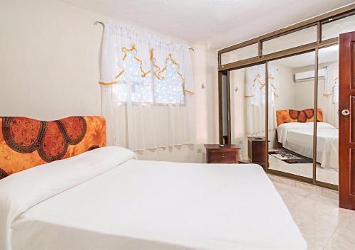 - une chambre avec un lit blanc et un miroir dans l'établissement Altagracia Apartments Santo Domingo, à Saint-Domingue