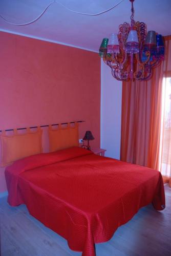 a red bedroom with a red bed with a chandelier at La Rosa dei Venti Resort in Piombino