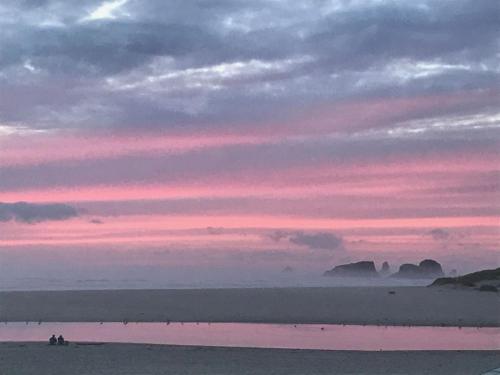 a sunset over the beach with people on the beach at Webb's Scenic Surf in Cannon Beach