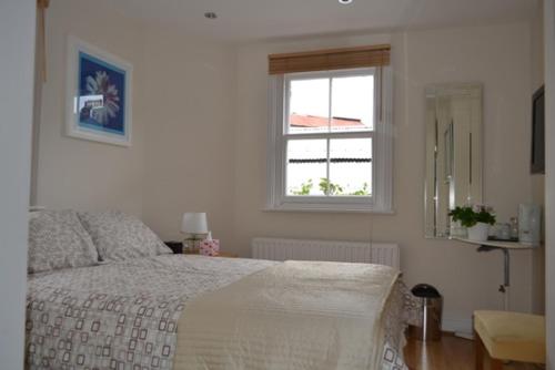 sypialnia z łóżkiem i oknem w obiekcie 69TheGrove w Londynie