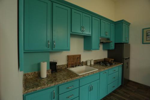a kitchen with green cabinets and a sink at Trojan House in Ensenada