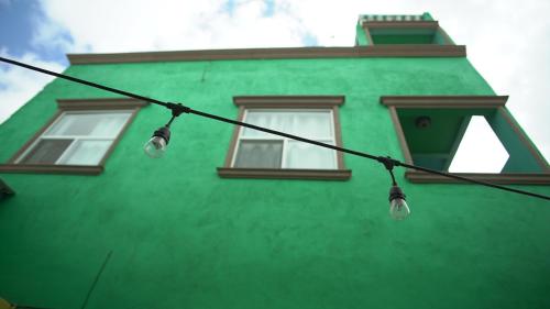 a green building with two windows and lights on a wire at Trojan House in Ensenada