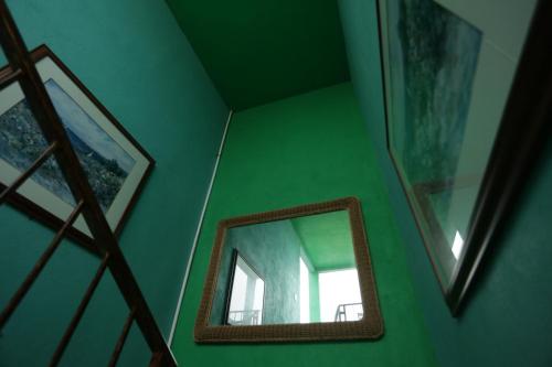 a mirror on a green wall in a room at Trojan House in Ensenada
