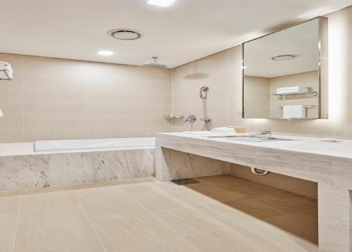 a bathroom with two sinks and a tub and a mirror at Skybay Hotel Gyeongpo in Gangneung