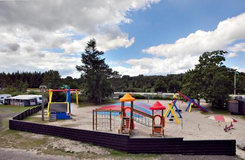 un parque infantil con un colorido equipo de juegos en la arena en Svalereden Camping Rooms, en Saeby