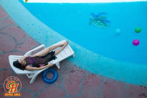 a woman laying on a raft next to a swimming pool at Hotel Gina in Tecomán