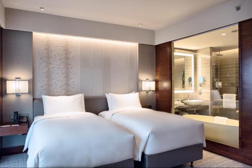 a hotel room with two beds and a bathroom at Amara Shanghai in Shanghai