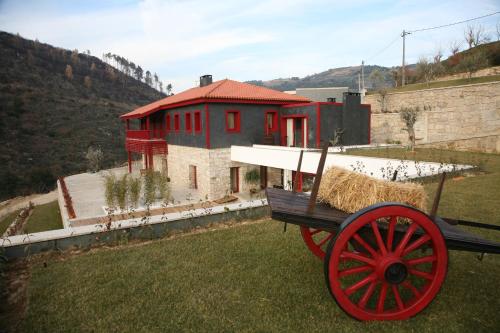a red wagon with hay in front of a house at Quinta dos Padres Santos, Agroturismo & Spa in Lamego