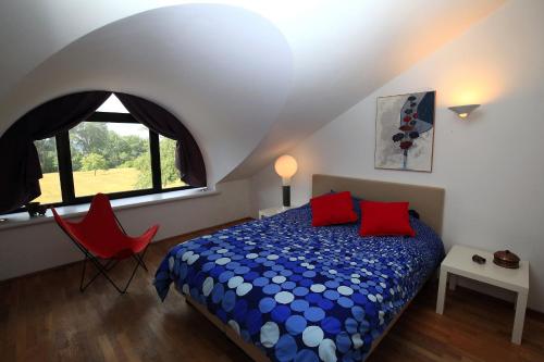 a bedroom with a bed and a red chair at La Petite Bruyere De Renaix in Ronse