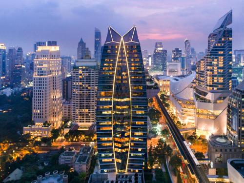 um edifício alto numa cidade à noite em The Okura Prestige Bangkok em Bangkok