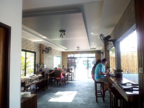 a group of people sitting at a bar in a restaurant at Billabong Hotel and Cafe in Baan Tai