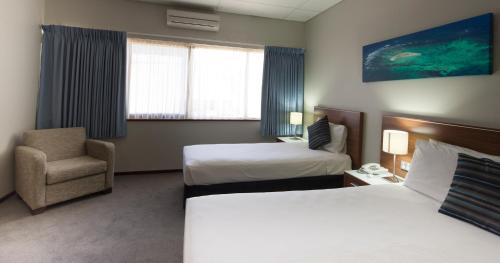 a hotel room with two beds and a chair at Ocean Centre Hotel in Geraldton