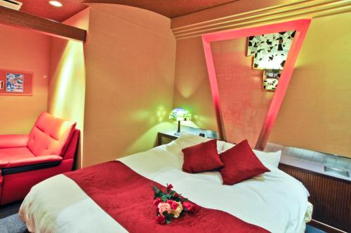 a bedroom with a large bed and a red chair at Hotel Joyplus (Love Hotel) in Onga