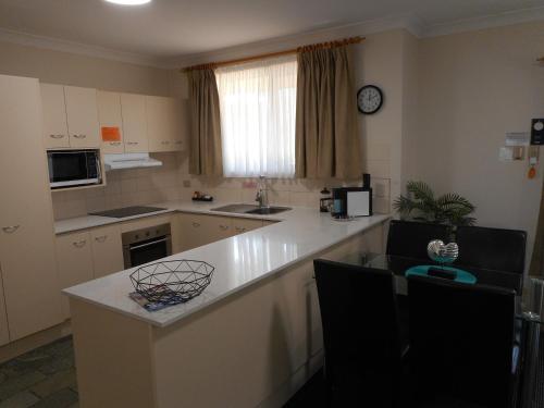 a kitchen with a white counter top and a sink at Beaches Serviced Apartments in Nelson Bay