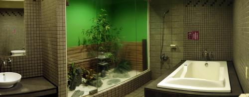 a bathroom with a tub and a green wall with plants at Beckham Motel in Luzhu