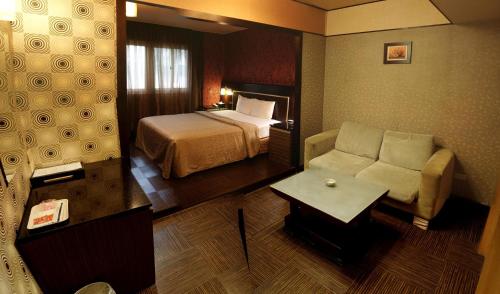 Habitación de hotel con cama y sofá en Beckham Motel, en Luzhu