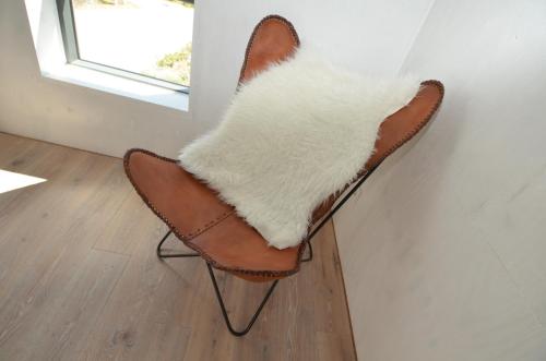 ein brauner und weißer Stuhl mit einem weißen Teppich drauf in der Unterkunft The Strandwood House in Gager in Gager