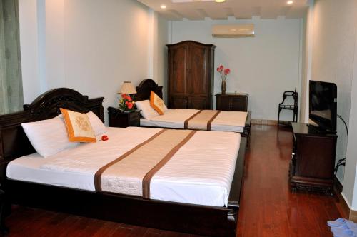 a bedroom with two beds and a flat screen tv at Thai Binh II Hotel in Hue