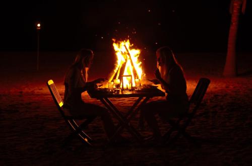 two women sitting at a table in front of a fire at Dolphin Beach Resort in Kalpitiya