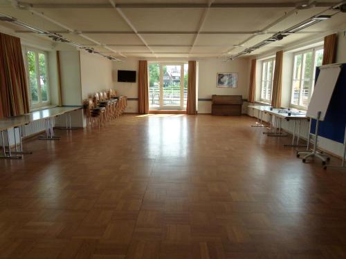 Habitación grande con suelo de madera, mesas y ventanas. en Jugendherberge Tübingen en Tübingen