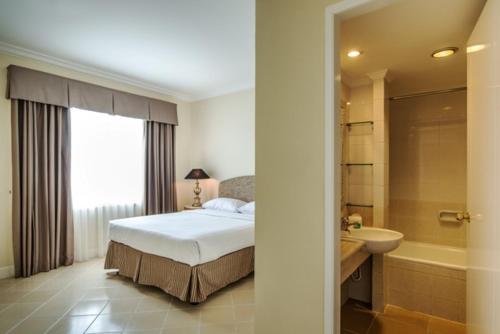 a bedroom with a bed and a tub and a sink at Batavia Apartments, Hotel & Serviced Residences in Jakarta