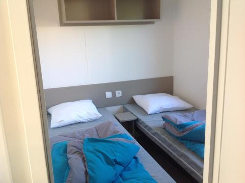 une petite chambre avec deux lits et un miroir dans l'établissement MOBILHOME DANS LES LANDES, à Saint-Julien-en-Born