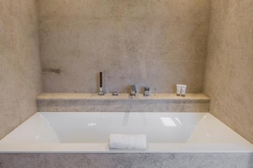 a bath tub in a bathroom with a sink at Domaine de Rymska & Spa - Relais & Châteaux in Saint-Jean-de-Trézy