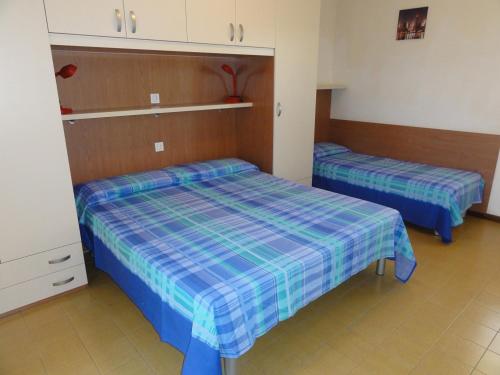 ビビオーネにあるSimma - Appartamentiの青と緑のシーツが備わる客室のベッド2台