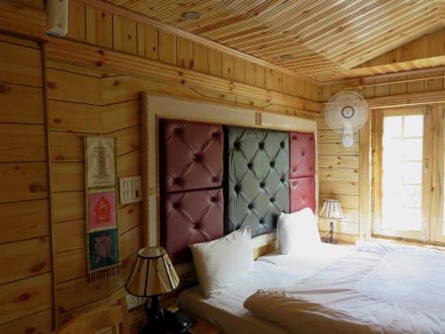 1 dormitorio con 1 cama en una cabaña de madera en Hotel Nezer Holiday Inn, en Leh