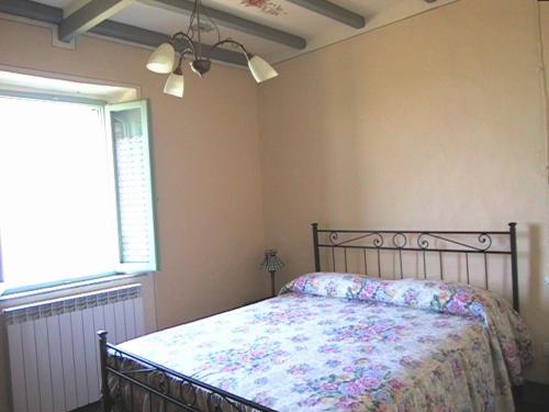 una camera da letto con un letto con copriletto floreale e una finestra di Podere Soccorso a Montalcino