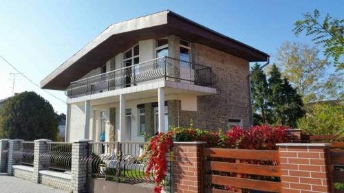 バラトンフェニヴェシュにあるFenyves Villaのレンガ造りの家(バルコニー、フェンス付)