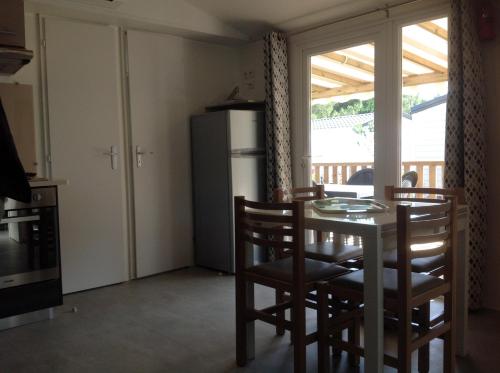 une cuisine et une salle à manger avec une table et des chaises dans l'établissement MOBILHOME DANS LES LANDES, à Saint-Julien-en-Born