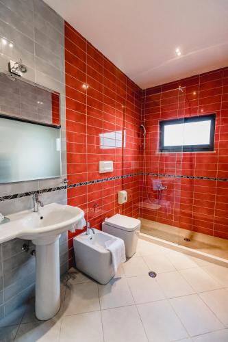 a bathroom with a sink and a toilet and red tiles at Green House Hotel & Restaurant in Tirana