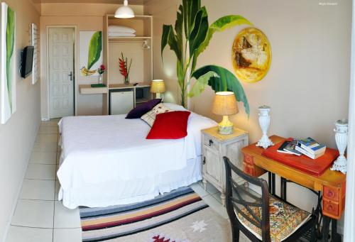 a bedroom with a bed and a desk with a desk at Pousada Via Brasil in Morro de São Paulo