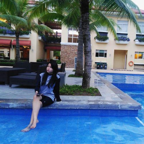 a woman sitting on the edge of a swimming pool at Two-Bedroom at San Remo Oasis in Cebu City