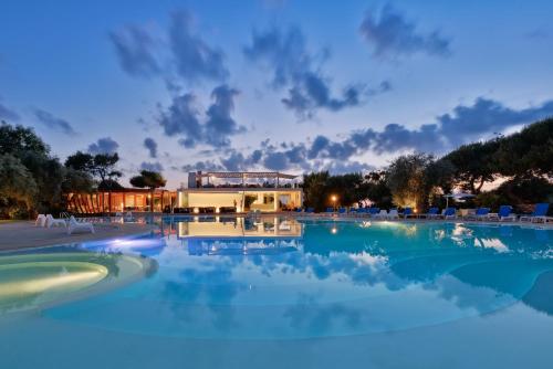 a swimming pool with blue water at night at Trezene Village in Castellabate