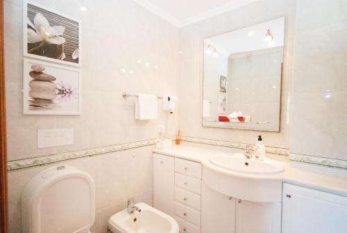 a white bathroom with a sink and a toilet at Grace Villa in Aldeia de Juso