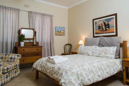 a bedroom with a bed and a chair and a mirror at Island View f5 in Melkbosstrand