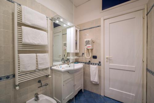 Baño blanco con lavabo y espejo en House Matilde, en Sorrento